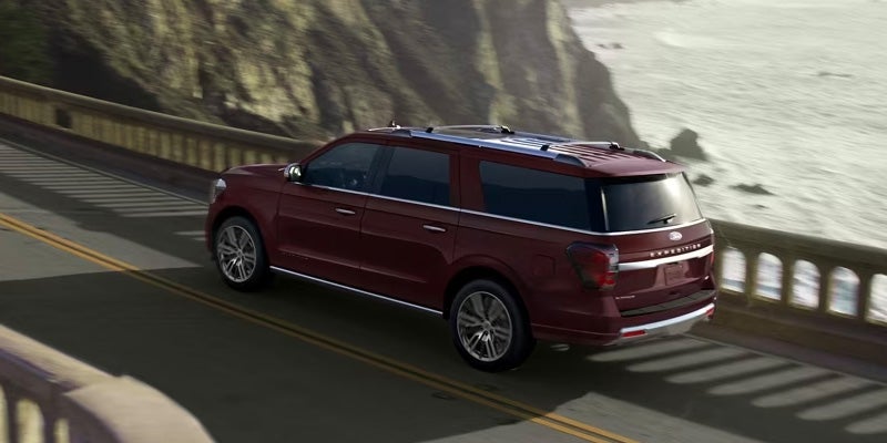 Una Ford Expedition conduciendo por una carretera con vista al mar detrás.