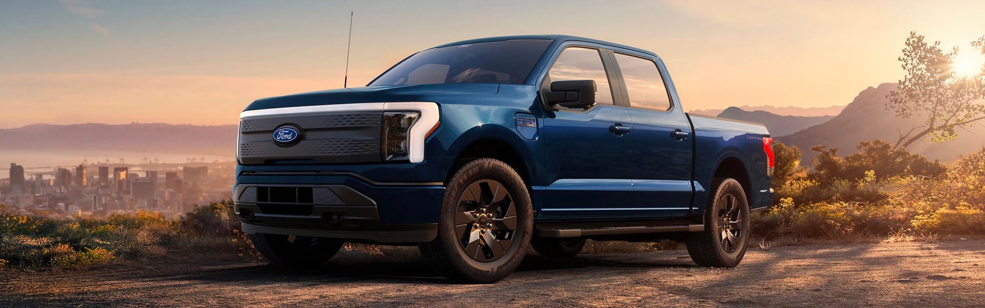 Una camioneta pickup de la serie F-150 Lightning de Ford estacionada en un mirador escénico al atardecer.
