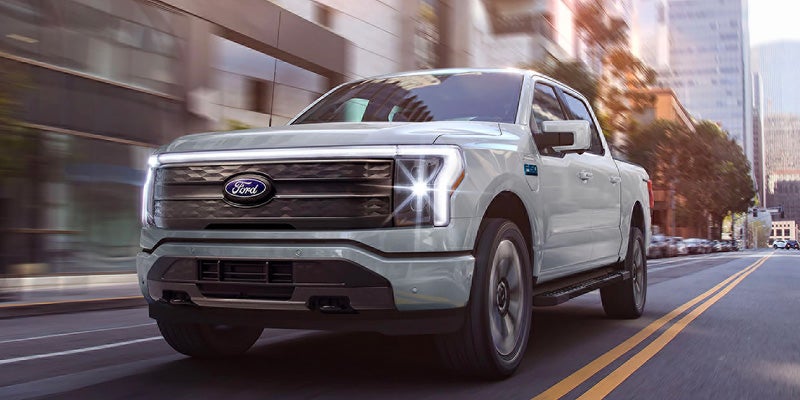 Una camioneta pickup F-150 Lightning de Ford vista de frente con los faros encendidos.