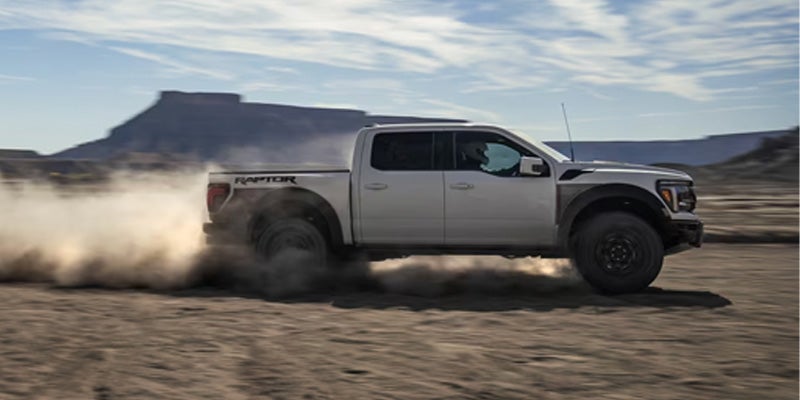 Un Ford F-150 avanza por tierra desértica generando una estela de arena elevada.